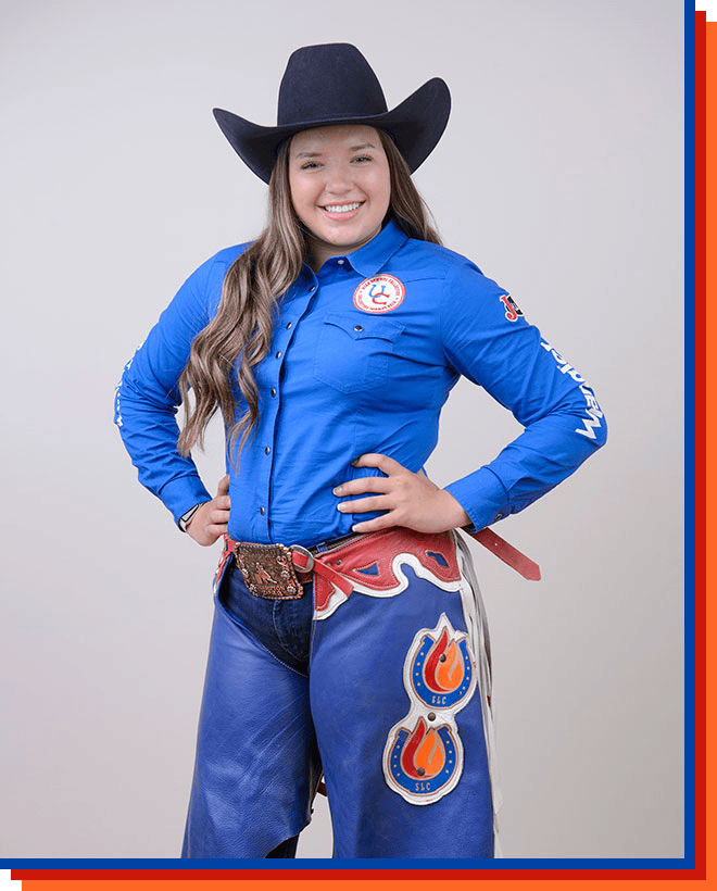 Paige Clem smiling at the camera, posing wearing a cowgirl hat and a blue shirt.